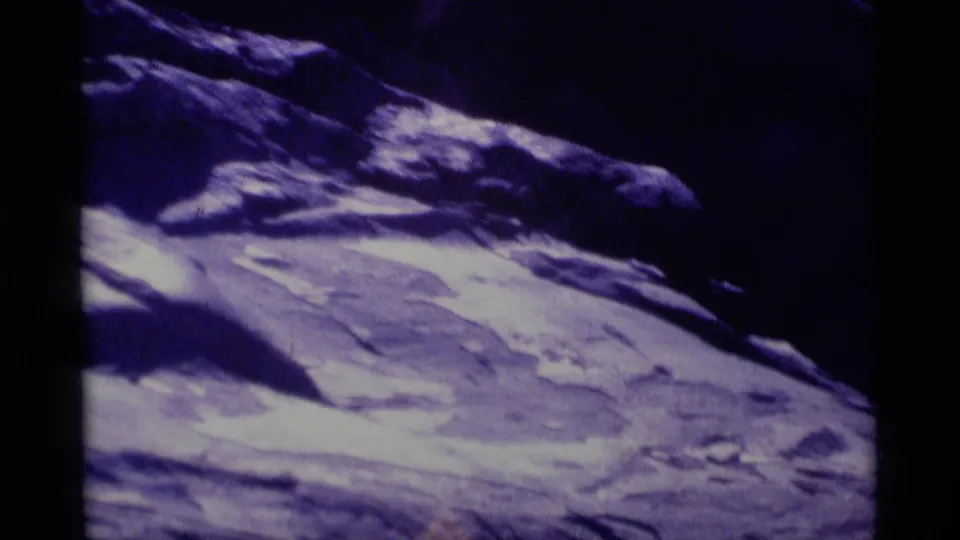 Closer 8mm view of Minaret Wilderness mountainside, with pale textured terrain leading up toward a dark rocky ridge.