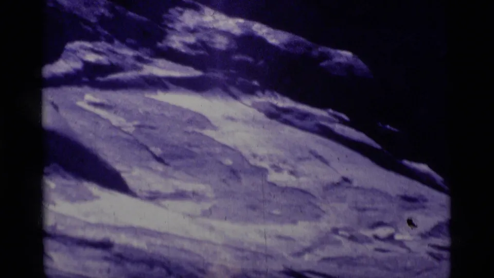 End frame from a 1975 Minaret Wilderness 8mm zoom, showing pale rugged terrain under a dark rocky upper slope.