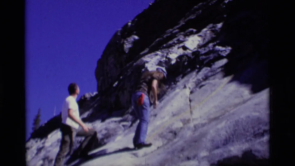 1975 8mm footage of one climber observing another near a rope on a sunlit granite slope in the Minaret Wilderness.