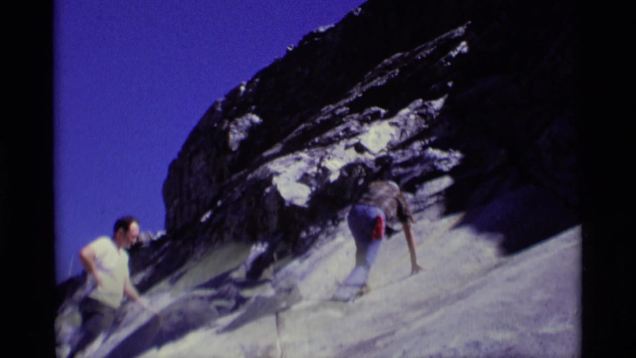 1975 California wilderness frame with one adult hiker climbing a rocky incline while a second hiker remains below.