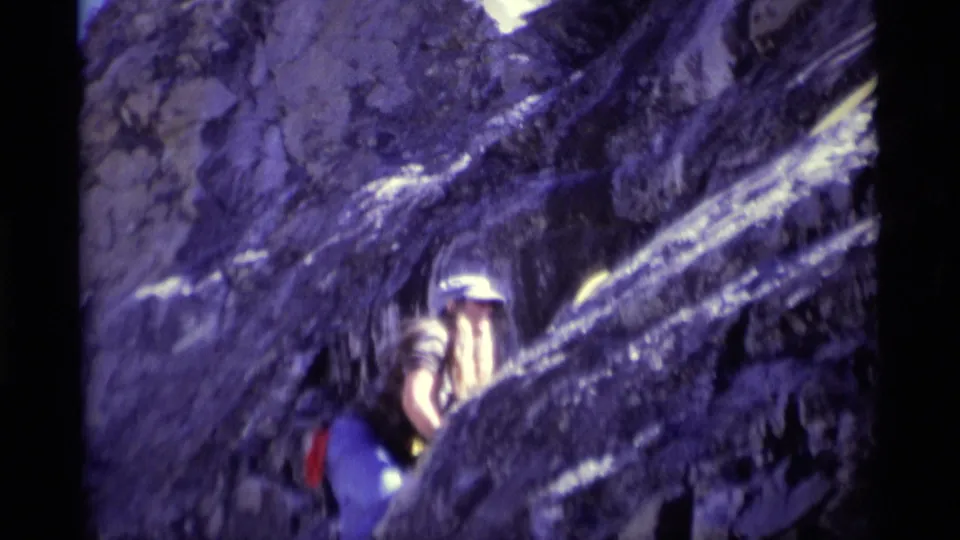 1975 California mountain frame showing the climber near the rock edge, with white helmet and red gear visible.