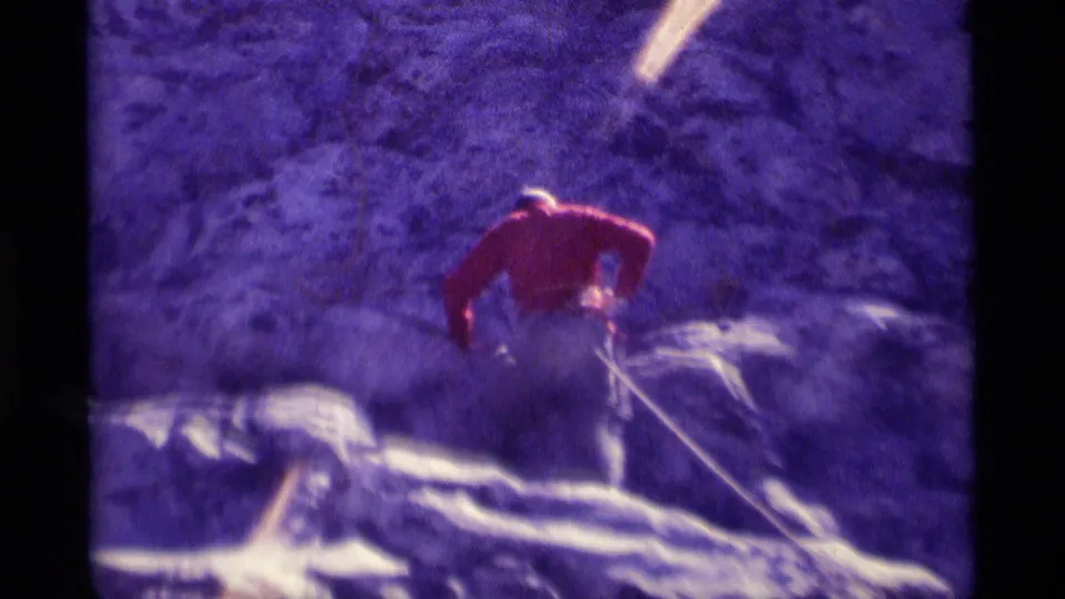 Closer 1975 8mm view of a red-shirted climber using a rope on steep rock in Minaret Wilderness, California.
