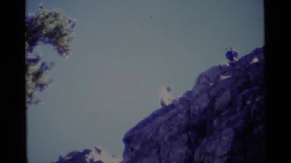 8mm home-movie frame from Minaret Wilderness with a hiker lower on the rocky slope and another person above against the sky.