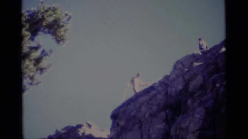 1975 8mm frame from Minaret Wilderness showing one climber on a rock face and another near the top edge.