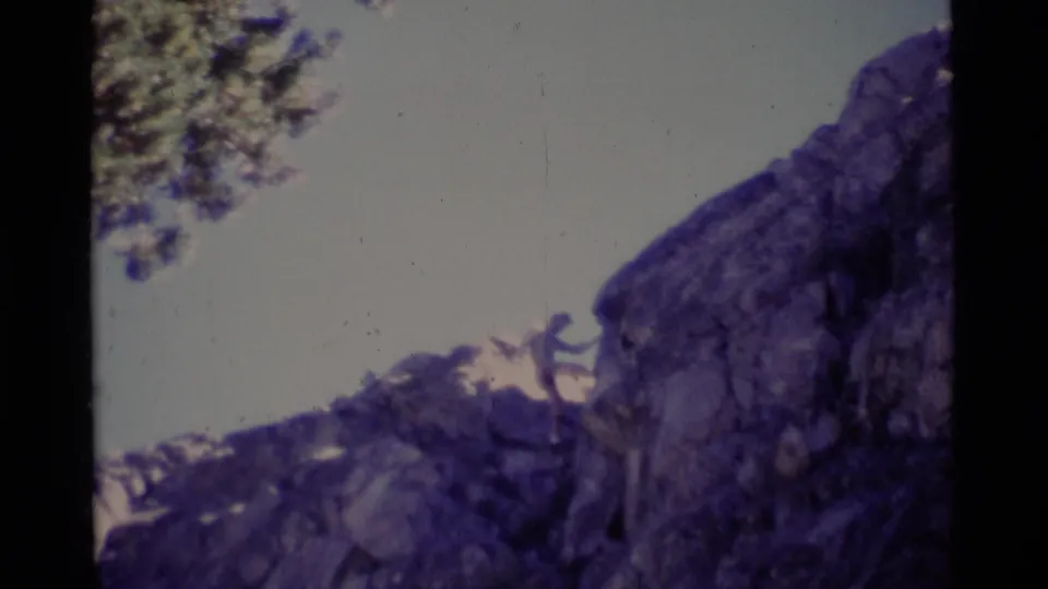 The final 1975 wilderness frame shows a person descending the cliff, with another figure or gear near the upper rock edge.