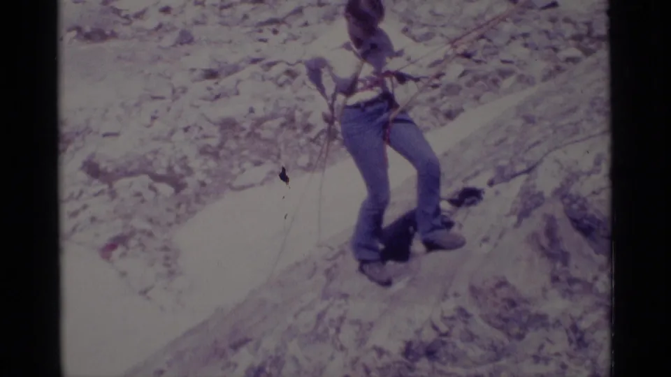 1970s 8mm frame showing a roped climber navigating a pale rocky slope in Minaret Wilderness.