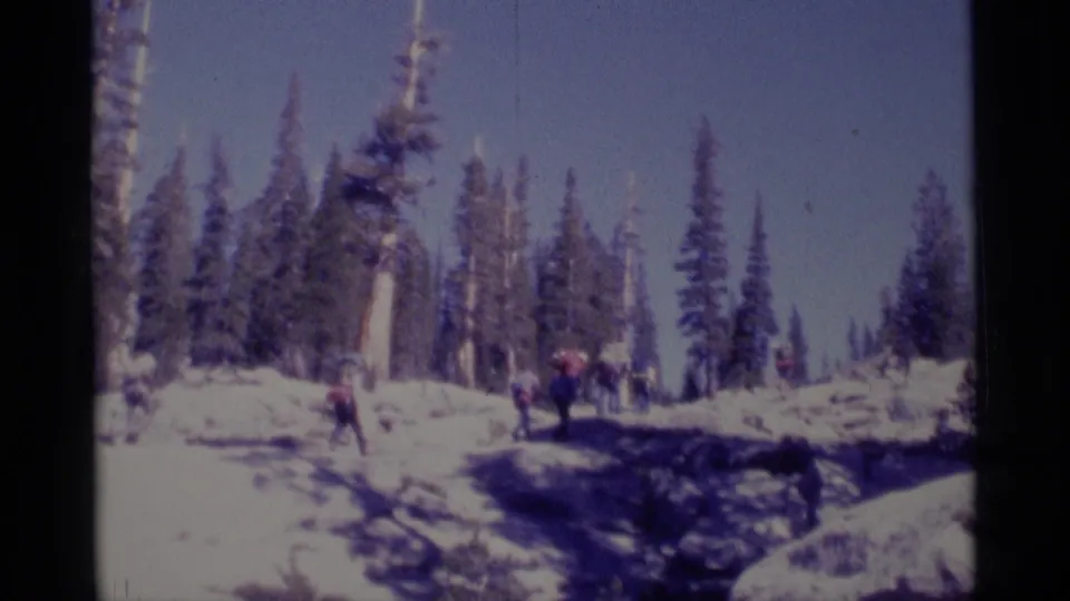 Backpackers appear in a wide snowy forest clearing during a 1975 Minaret Wilderness home-movie scene.