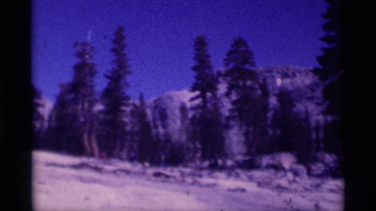 Snow-covered wilderness view in the Minaret Wilderness area, framed by evergreens and distant Sierra Nevada peaks.
