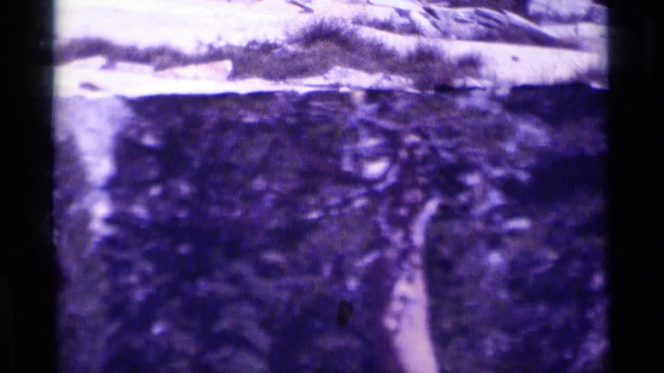 The 1975 Minaret Wilderness home-movie frame holds on a rocky mountain view with strong purple fading and handheld softness.