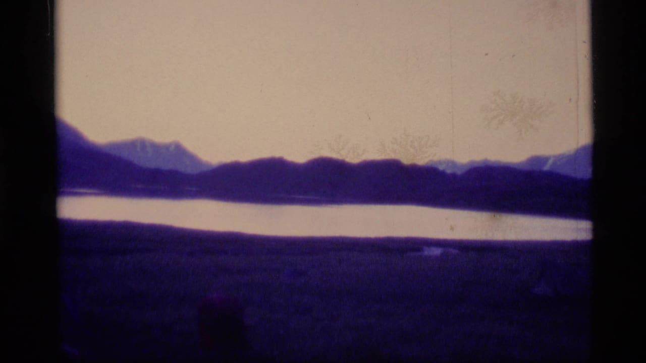 Dark mountain ridge and pale water under a washed sky, with black 8mm frame edges.