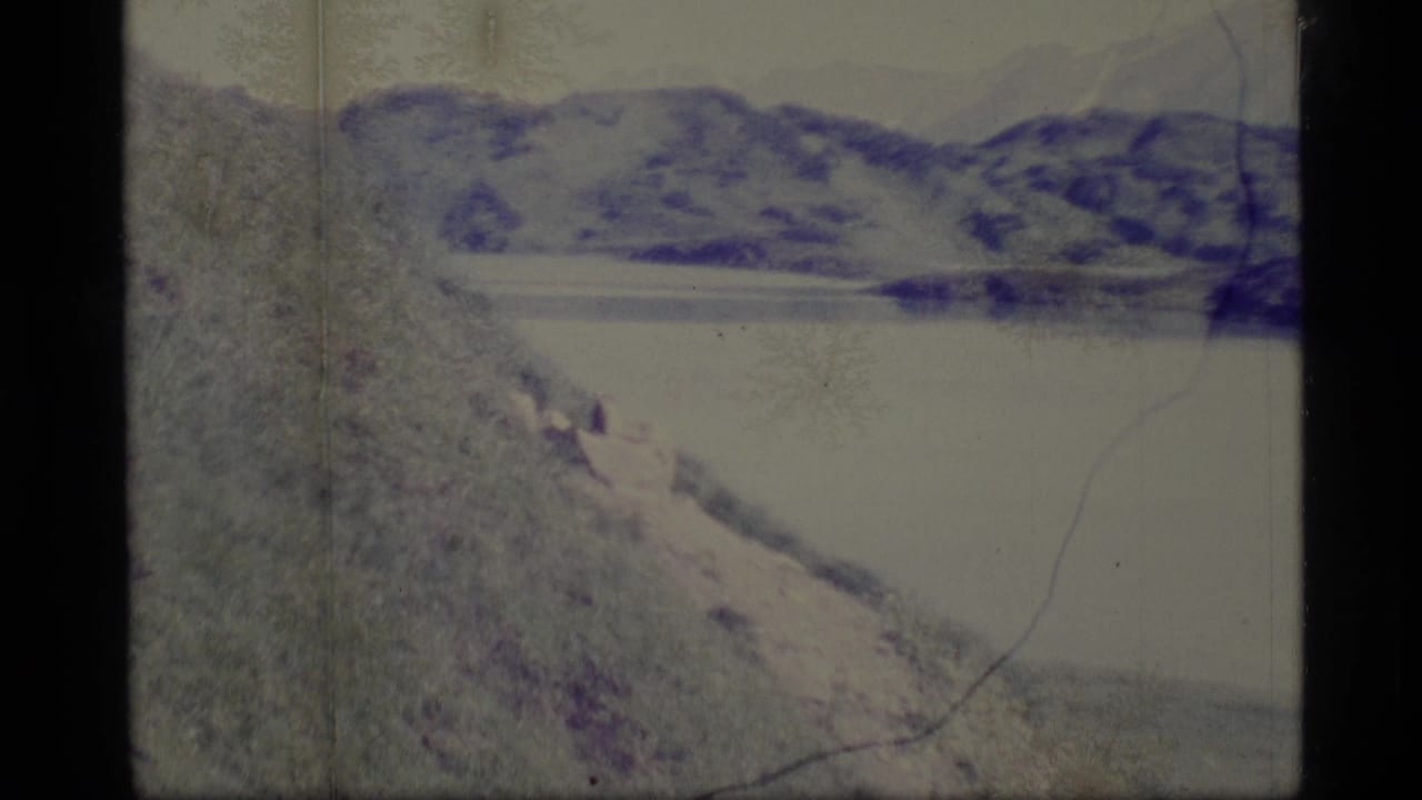 Faded mountain and lake view framed by 8mm film borders and scratches.