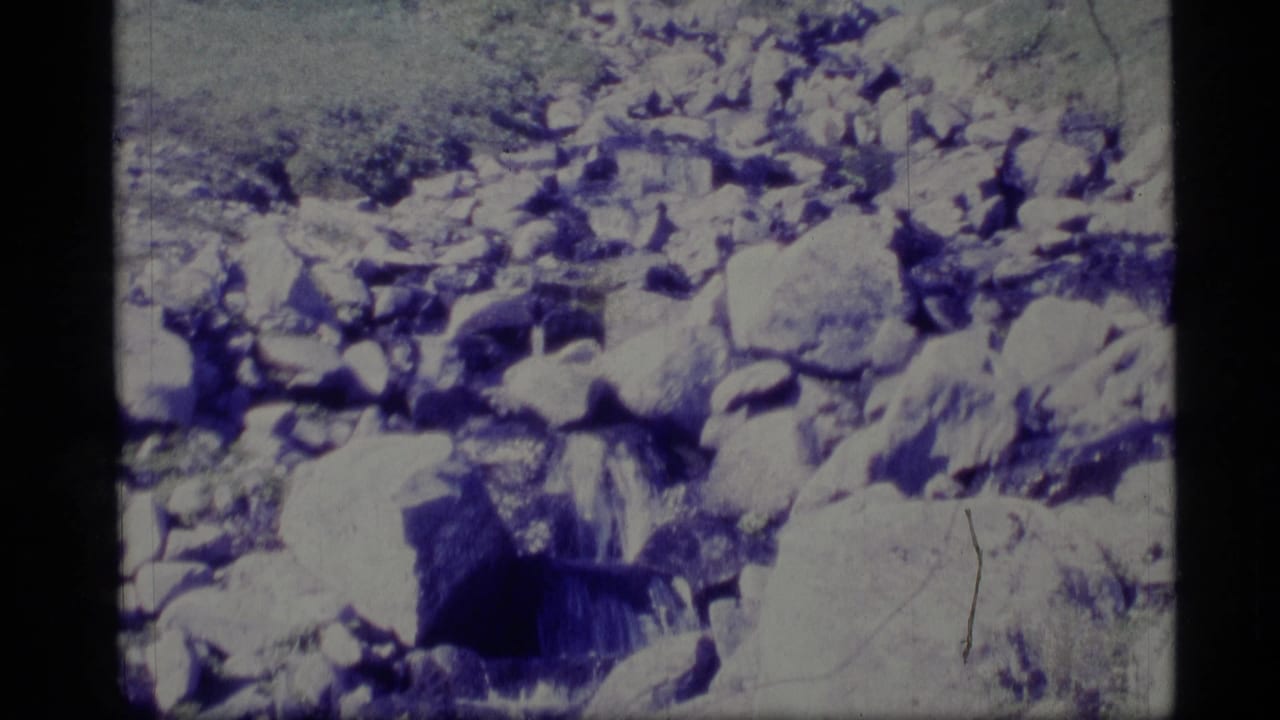 Small rocky waterfall or cascade seen through a scratched 8mm frame.