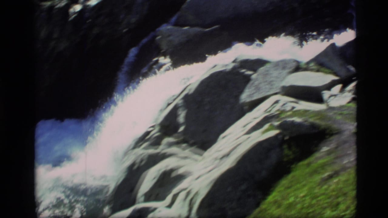Whitewater stream rushing past dark rocks and green moss.