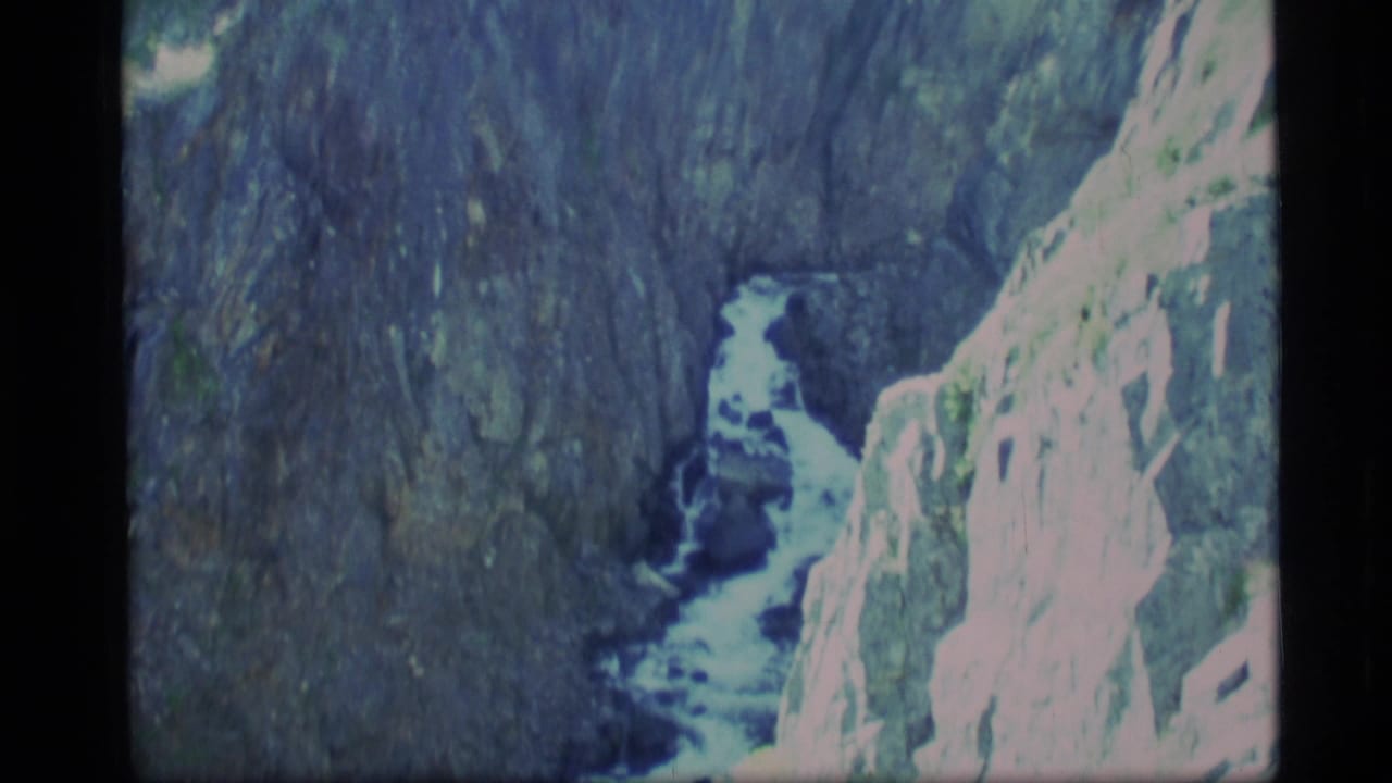 1977 Alaska 8mm frame showing a whitewater stream descending through a narrow rocky gorge with pale cliff faces.