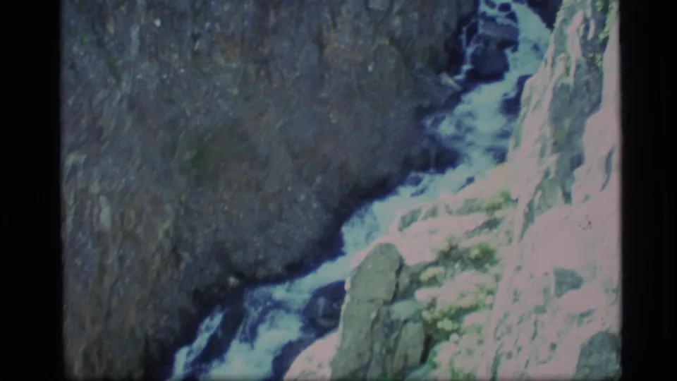 1977 Alaska 8mm frame showing foamy whitewater descending through a rocky mountain gorge.