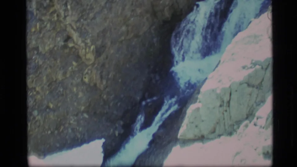 1977 Alaska 8mm frame looking along the lower waterfall channel, with white water cutting through dark rock.