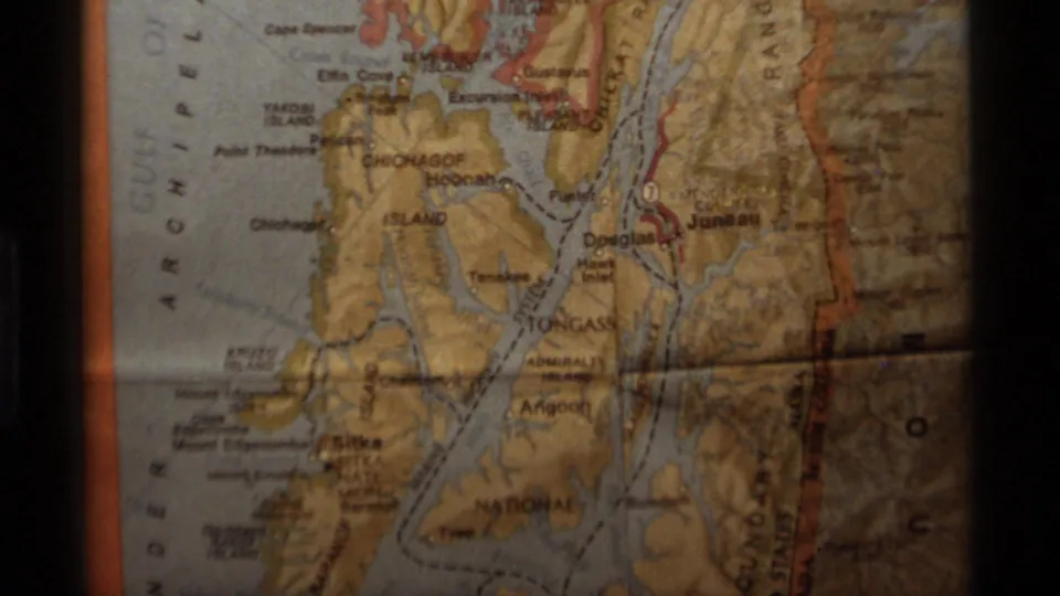 A close view of a paper Alaska map appears in the 1977 home movie, showing islands, waterways, and printed place names.