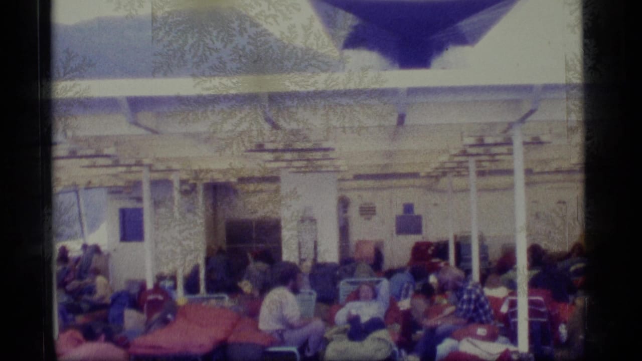 Passengers relax on lounge chairs under a covered ship deck.