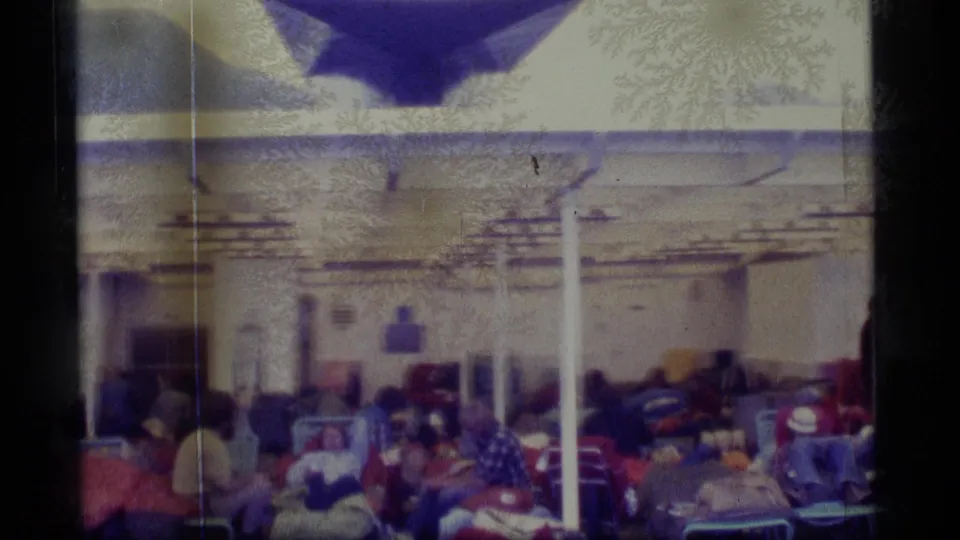 Passengers on a 1977 Alaska cruise sit and lounge close together under a ship-deck canopy.