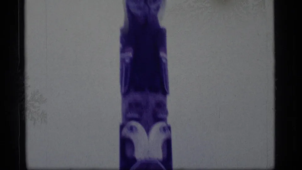 1977 Alaska 8mm frame showing the middle and lower carved sections, including an owl-like motif near the base.