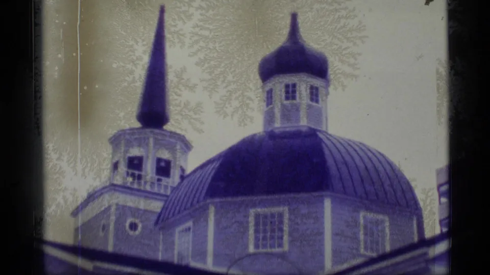 Closer 1977 Alaska 8mm view of a domed church roof, cupola, and neighboring steeple with soft focus and visible film wear.