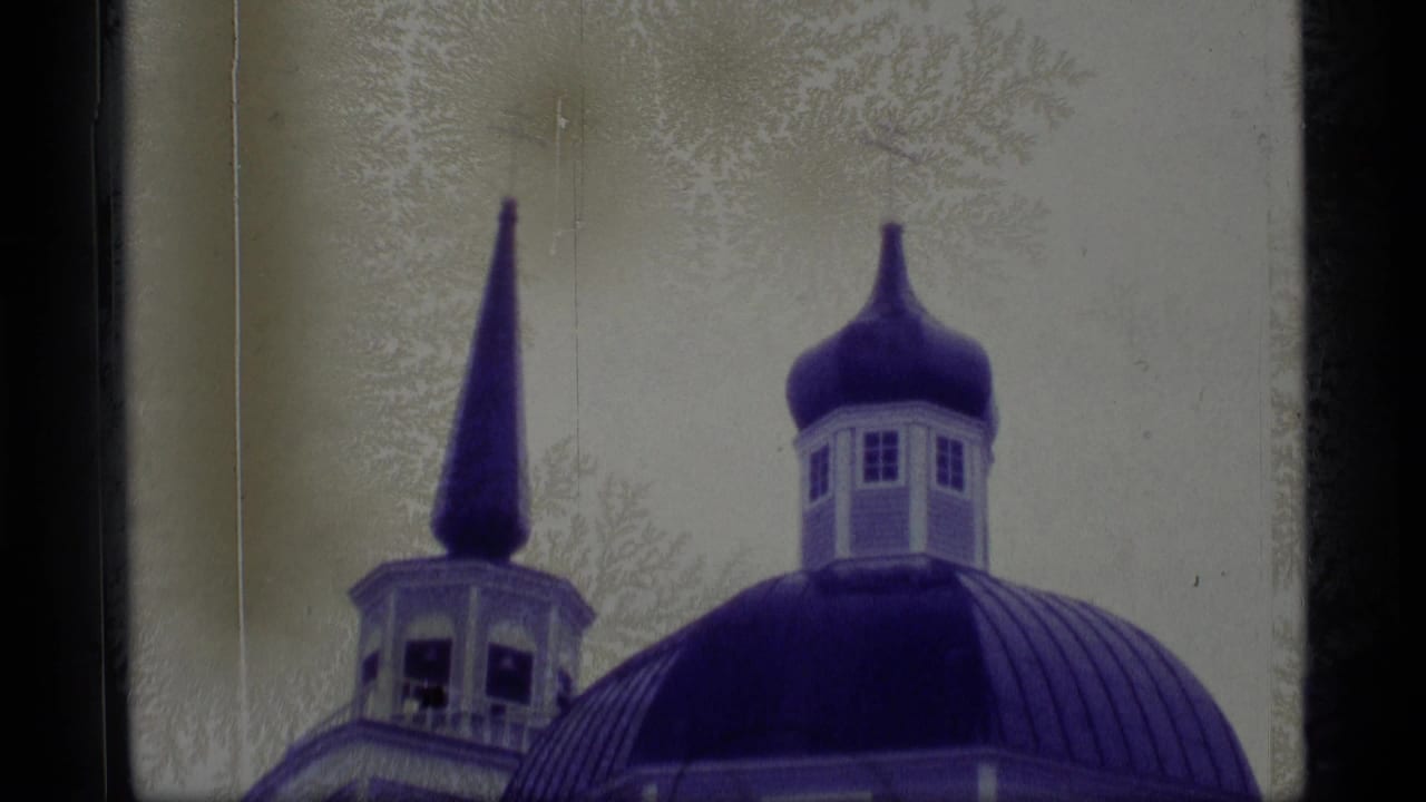 1977 Alaska 8mm frame showing a blue domed church roof, cupola, and pointed spire against a pale snowy background.
