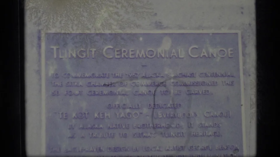 1977 Alaska 8mm close-up of the Tlingit Ceremonial Canoe plaque, its inscription softened by focus and film fading.