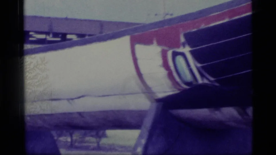 1977 Alaska frame showing a close crop of the canoe's painted side, including red and purple geometric forms on a light hull.