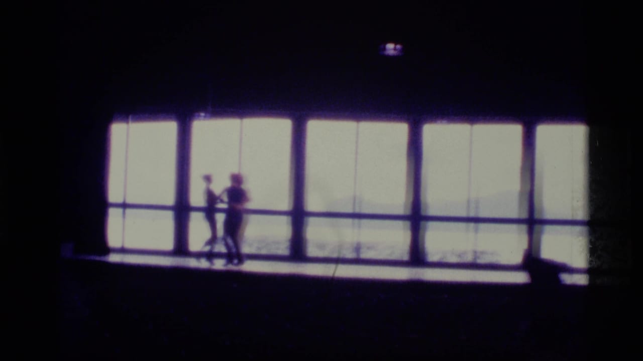 Three small silhouetted dancers stand before a wall of bright windows.