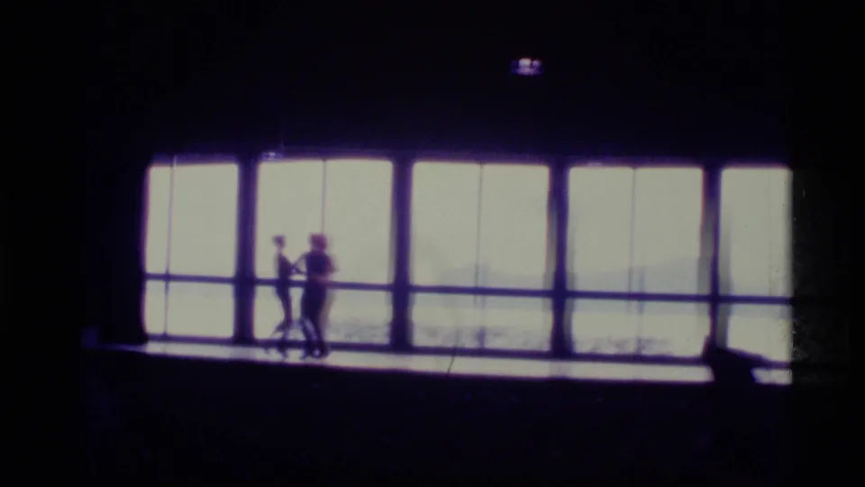 In the 1977 Alaska footage, three dancers appear in silhouette against large bright windows with a faint landscape beyond.