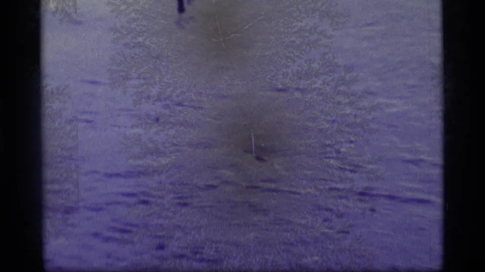 Faded 8mm frame showing murky floodwater with subtle ripples, scratches, and dark vertical film-edge borders.