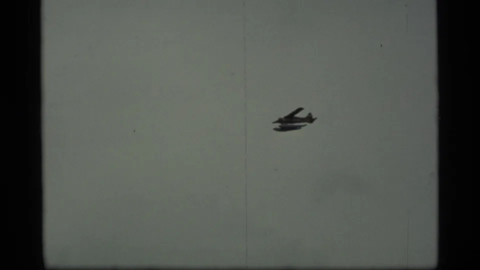 Closer 8mm view of the seaplane in the cloudy Alaska sky near the end of the approach shot.