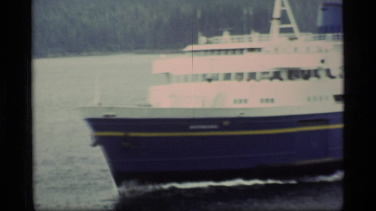 Close view of a blue-and-white passenger ferry bow moving across calm water.