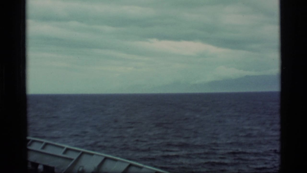 Open sea under a cloudy sky with the edge of a boat visible at lower left.