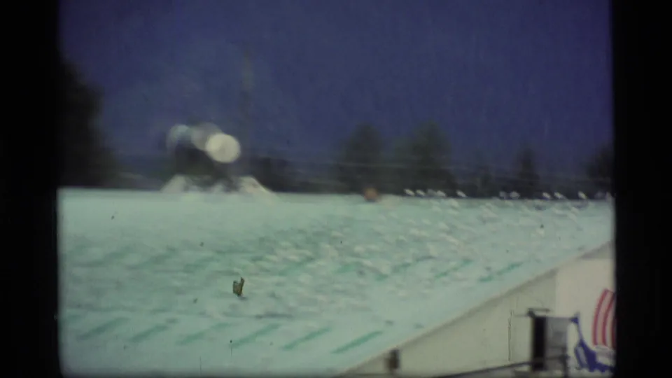 1977 Alaska port view with many seagulls scattered across a pale roof near the waterfront, seen through soft handheld 8mm footage.