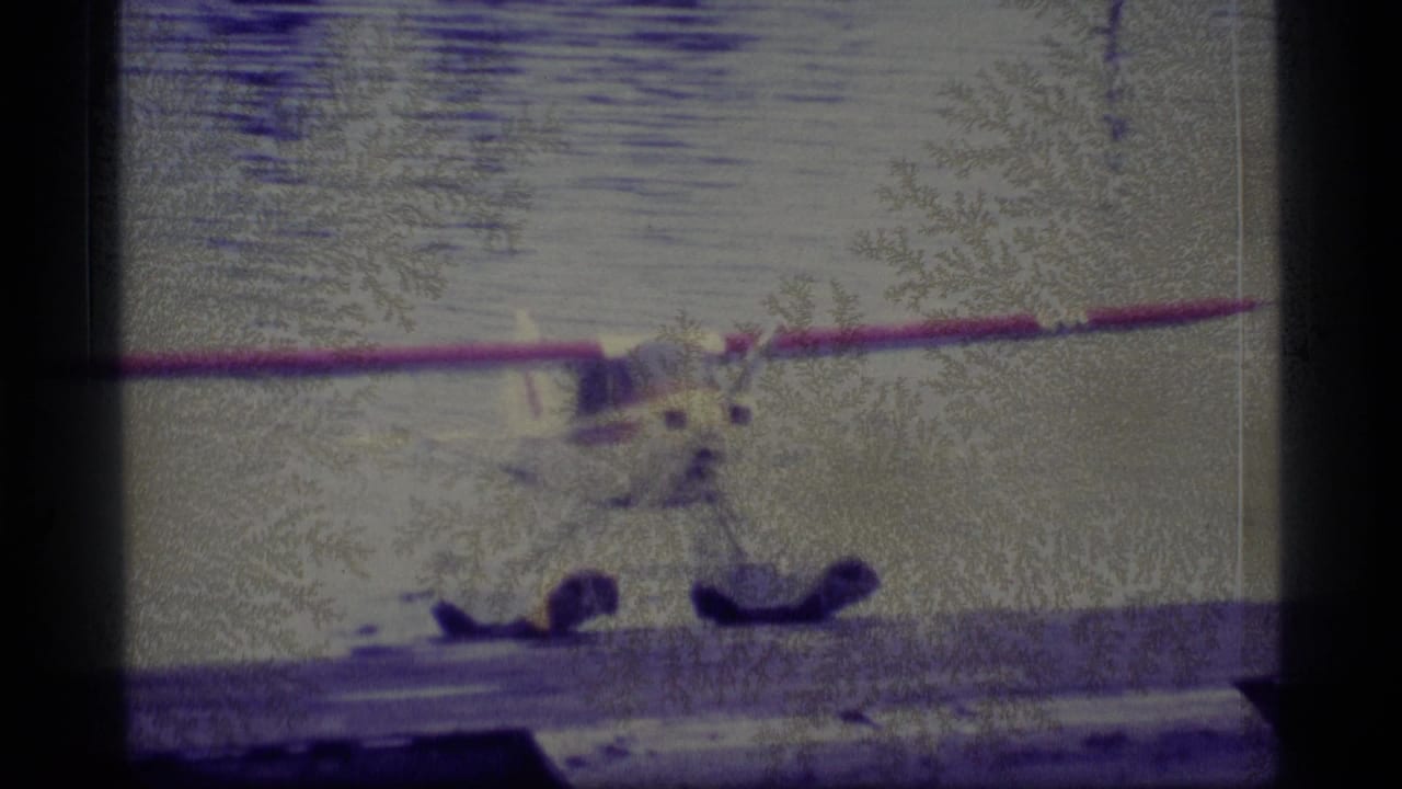 1977 Alaska 8mm frame showing a floatplane at the water’s edge, with soft focus, heavy grain, and dark gate borders.