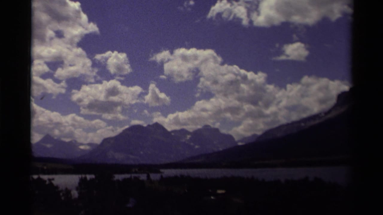 Mountain landscape with lake below and large clouds across the sky.