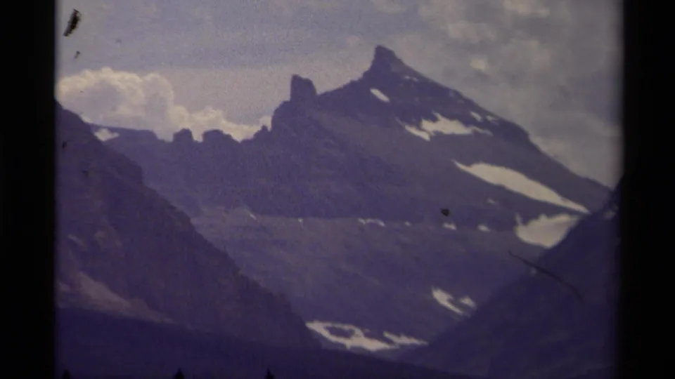 1979 Canada 8mm frame holding on the mountain range, with soft focus, snow patches, and dark film-edge framing.