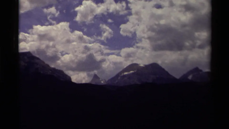 1979 Canada frame showing a dark mountain skyline, forested foreground, and dense cumulus clouds dominating the sky.