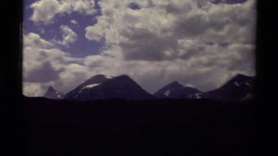 A 1979 Canada travel frame shows a wide mountain range, small snow patches, and thick clouds across the sky.