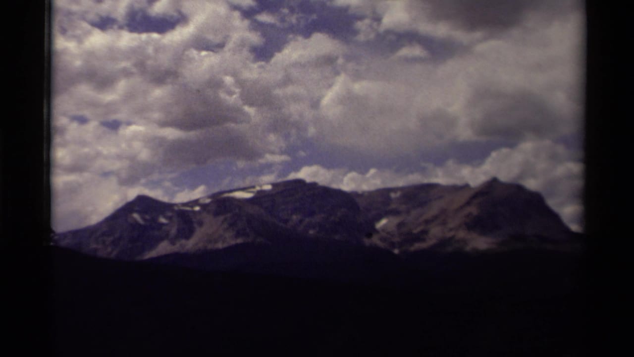 Mountain ridgeline under large clouds with dark borders around the frame.