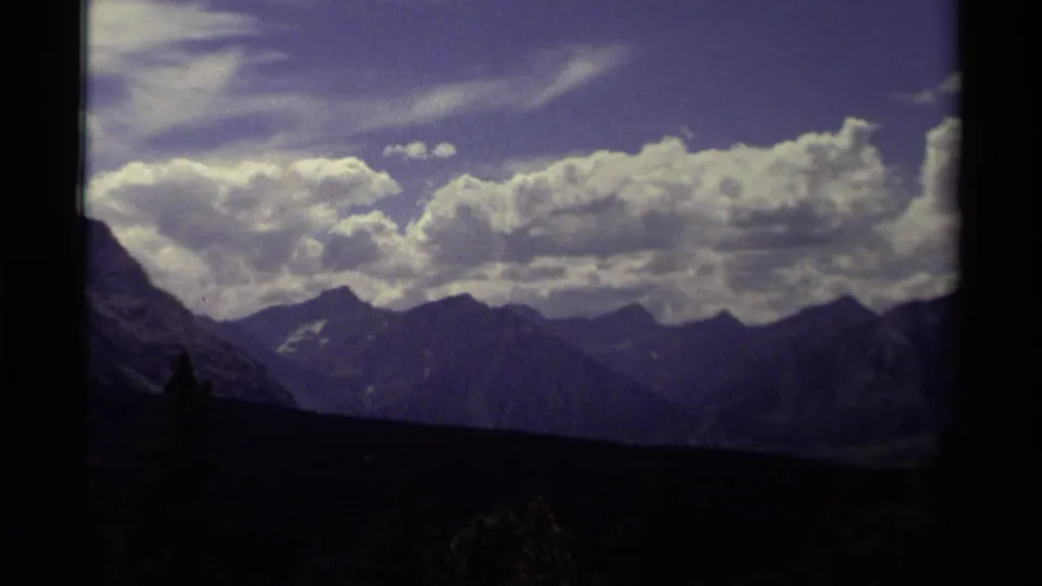 1979 Canadian 8mm frame of distant mountain peaks and a heavy cloud bank, with dark foreground land below.
