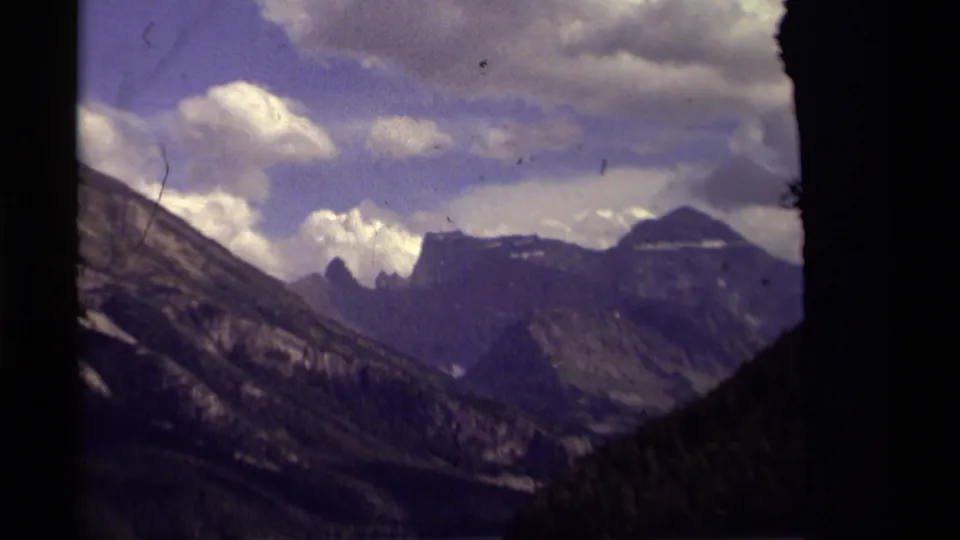 The final frame centers on the Canadian mountain range, with the lake below, clouds overhead, and dark tree forms along the edge.