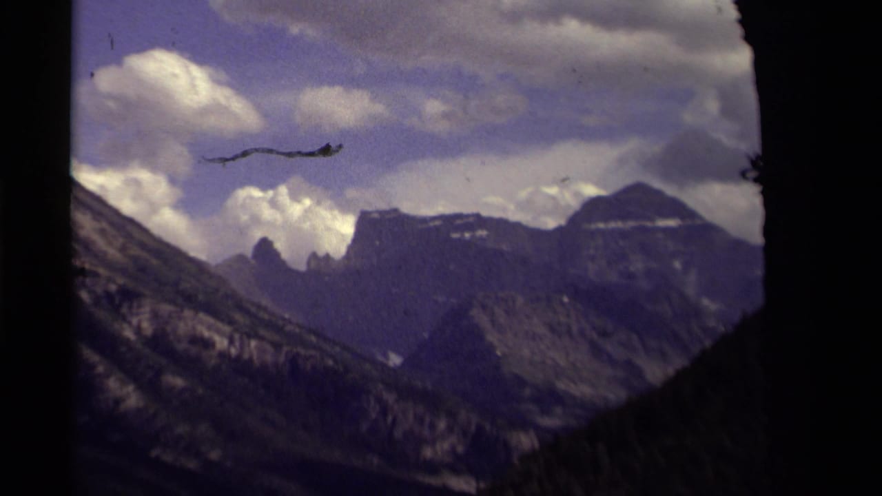 1979 8mm Canada footage showing high mountain peaks and shadowed slopes under a cloud-filled purple-blue sky.