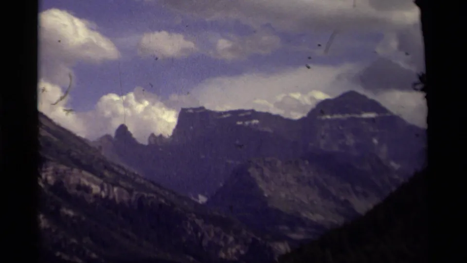 Canadian mountain landscape from 1979 home-movie footage, with distant peaks, heavy clouds, and visible film wear.