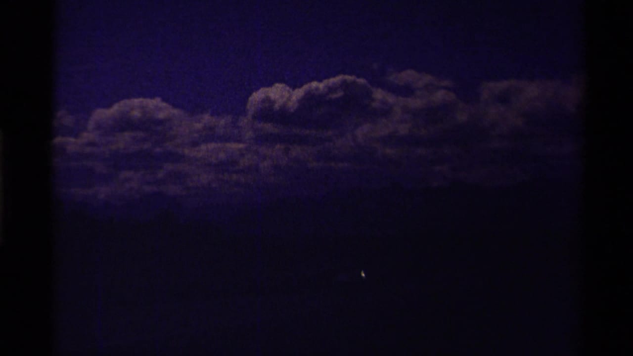 Dark purple-toned sky with low clouds and heavy film borders.