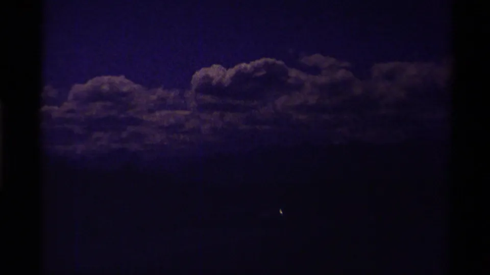 Purple-blue 8mm frame with faint cloud forms across a dark sky, likely an underexposed or color-shifted mountain-scenery shot.