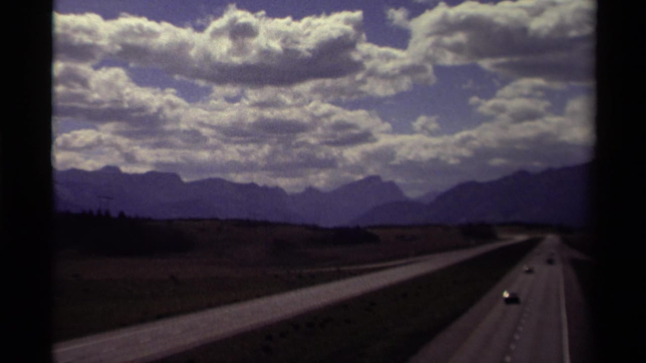 Divided highway leading toward distant mountains under a cloud-filled sky.