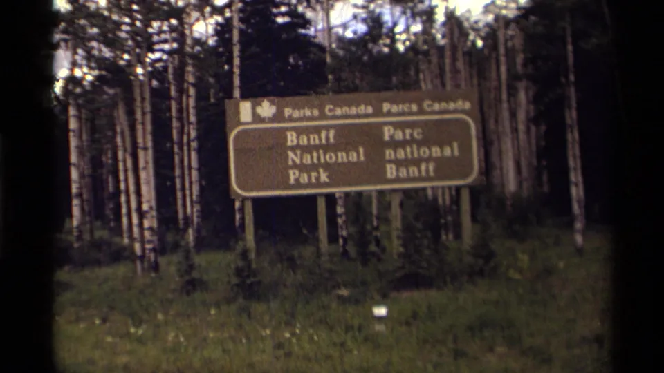 1979 Canadian travel frame showing a bilingual Parks Canada sign for Banff National Park among birch trees.