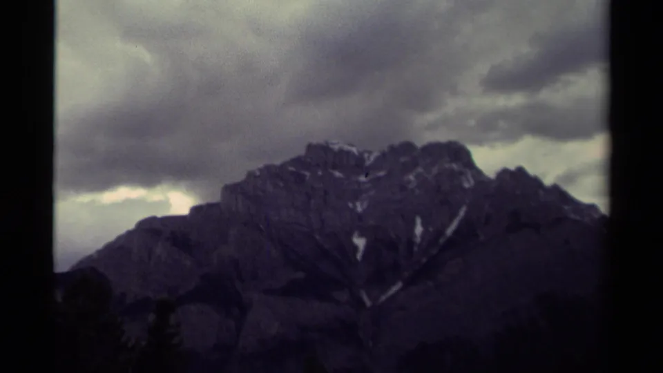 A wider 1979 Canadian mountain view shows a rocky ridge below dark clouds, with faint evergreen silhouettes at the base.